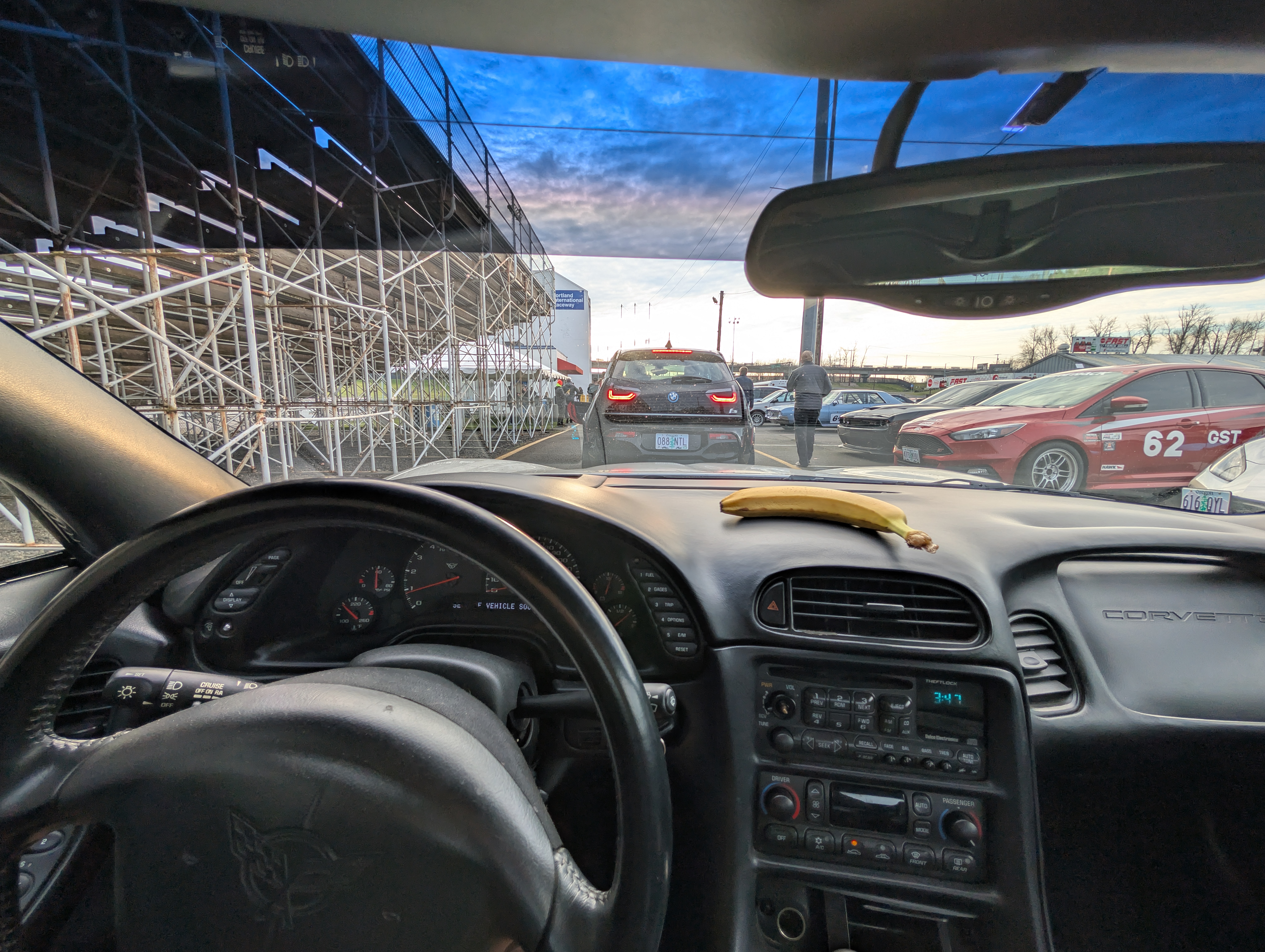 A shot from the inside of the Dead to Shred Corvette looking forward at the tech line at an autocross event. A car is parked in front with it's brake lights on.