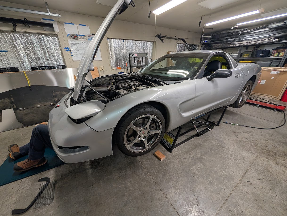 The Dead to Shred C5 Corvette in the air with a poor mechanic underneath it.