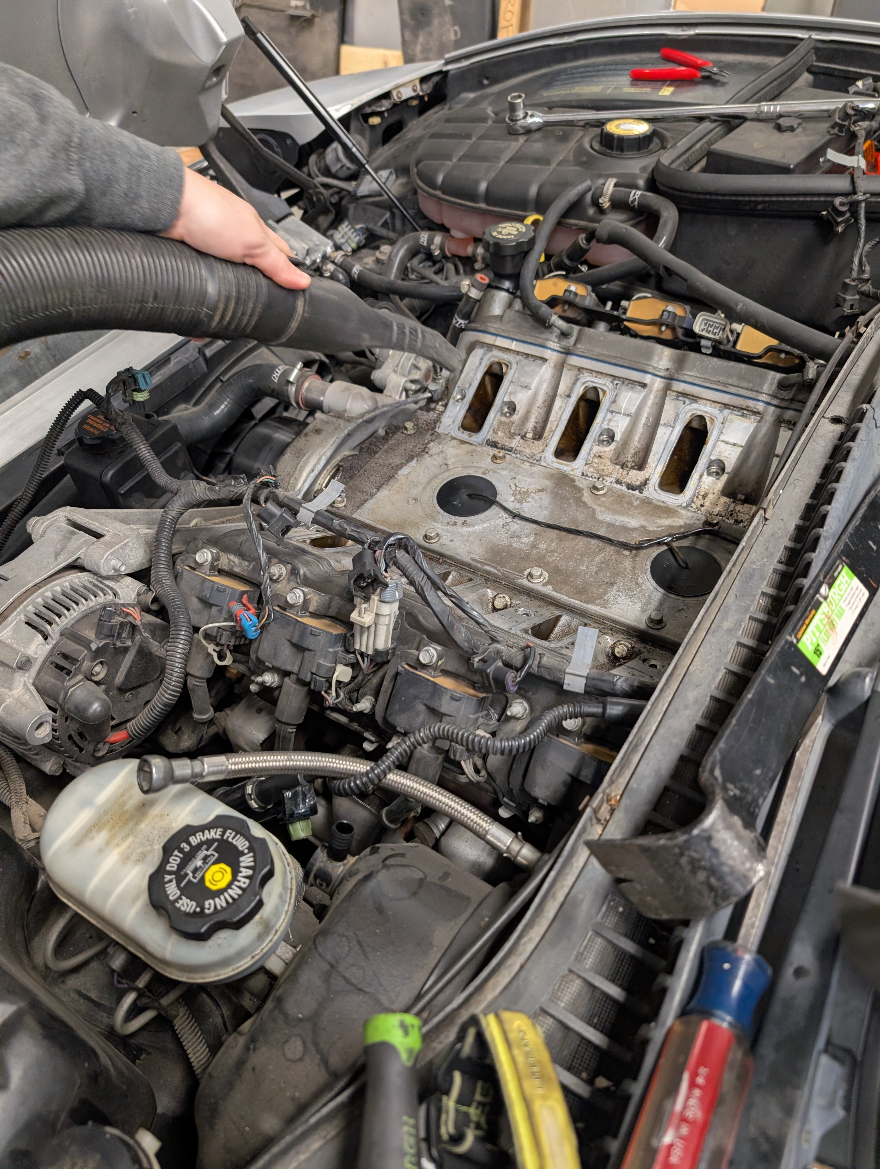 Vacuuming the valley cover area of a C5 Corvette to help ensure debris does not enter the engine.