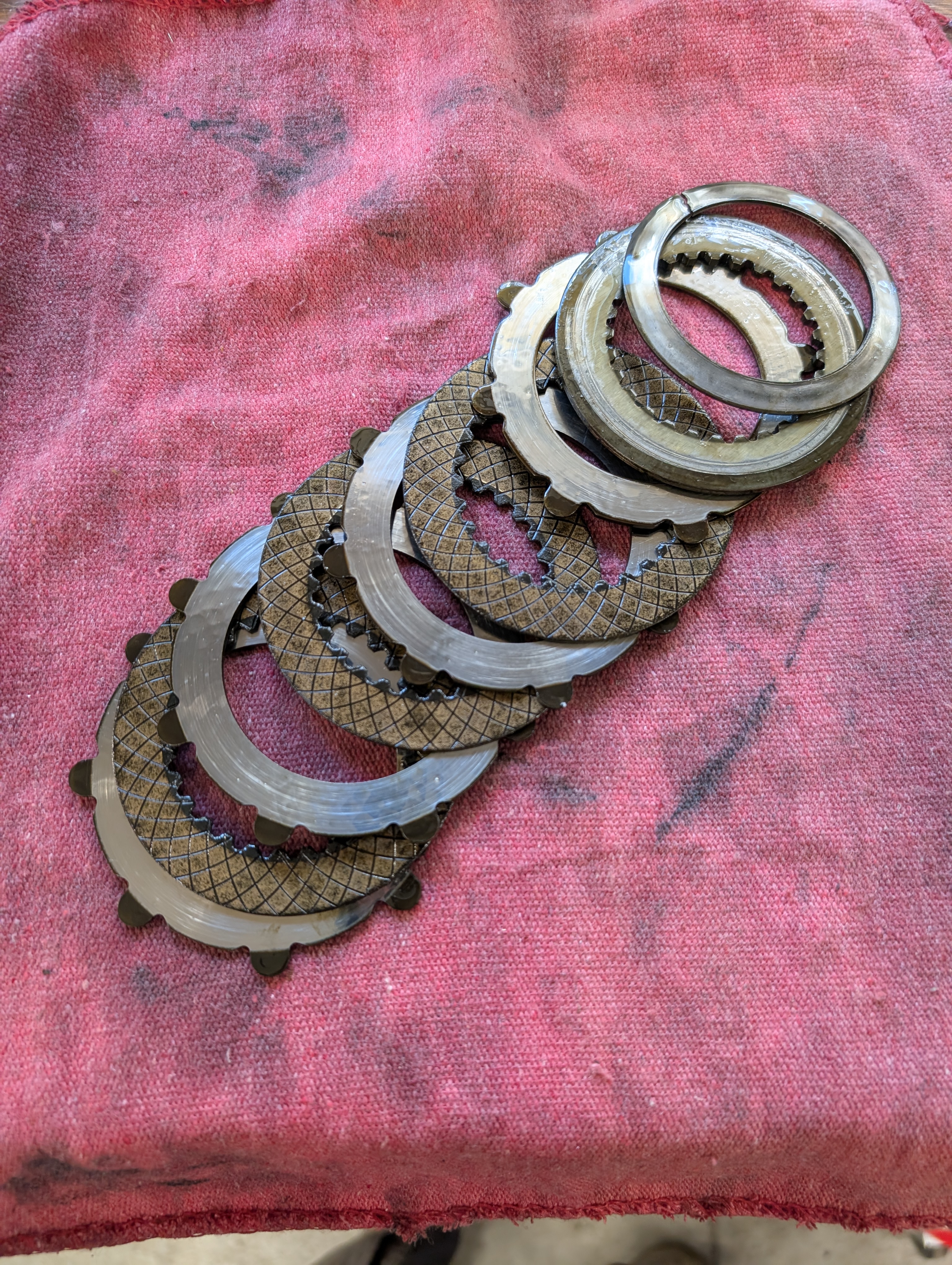 A C5 Corvette OEM clutch pack laid out to show all items and assembly order. The spring washer at the top of the stack is split due to a crack.