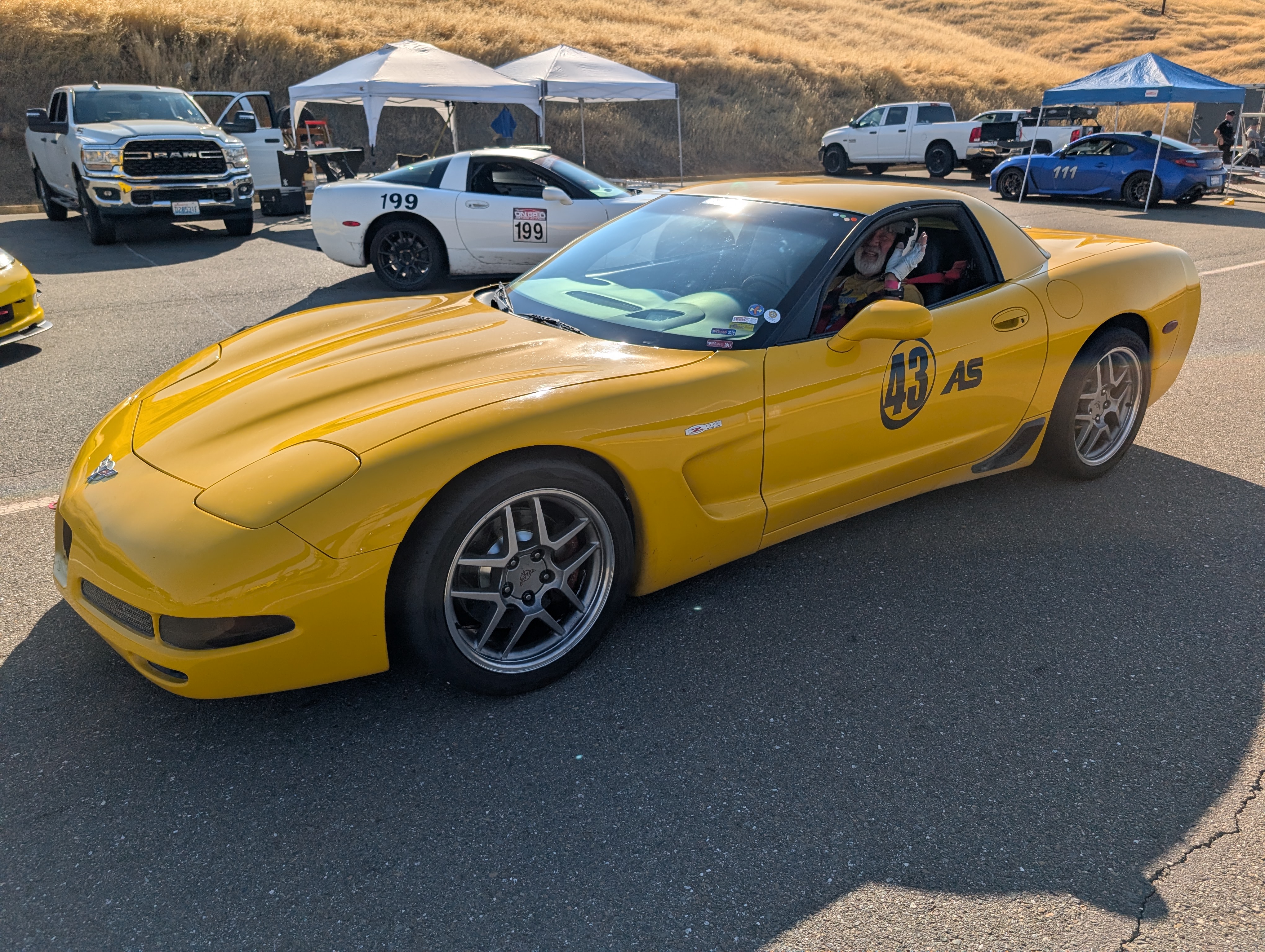 A fellow driving his yellow C5 Corvette #43, with a white C5 Corvette #199 behind it.