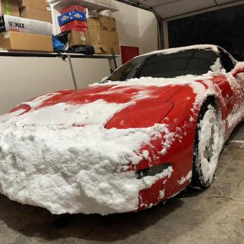 A red C5 Corvette with the front end plastered in snow