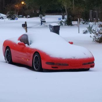 A red C5 Corvette with a dusting of snow ontop of it, with even the windshield blocked