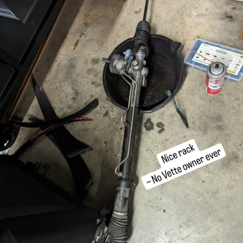 A C5 Corvette steering rock out of the car over a drain pan with the text "Nice Rack - No Vette owner ever"