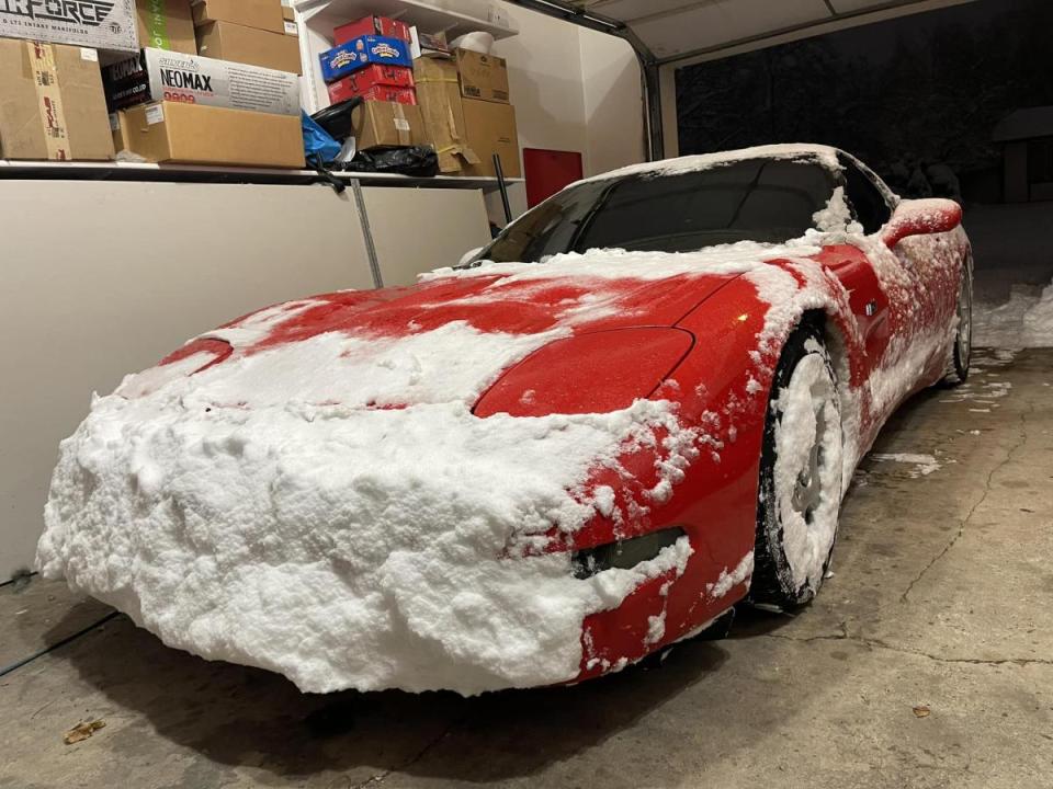 A red C5 Corvette with the front end plastered in snow