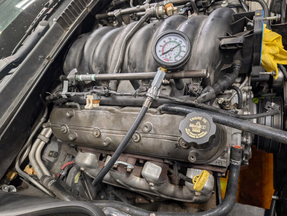 A 2001 C5 Corvette LS engine with a compression tester on it showing 190psi